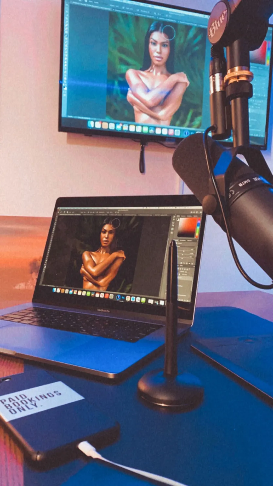 Workspace with editing monitors, microphone and Paid Bookings Only notebook